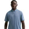 Man wearing a blue patterned polo shirt with a Nike logo on a light gray background