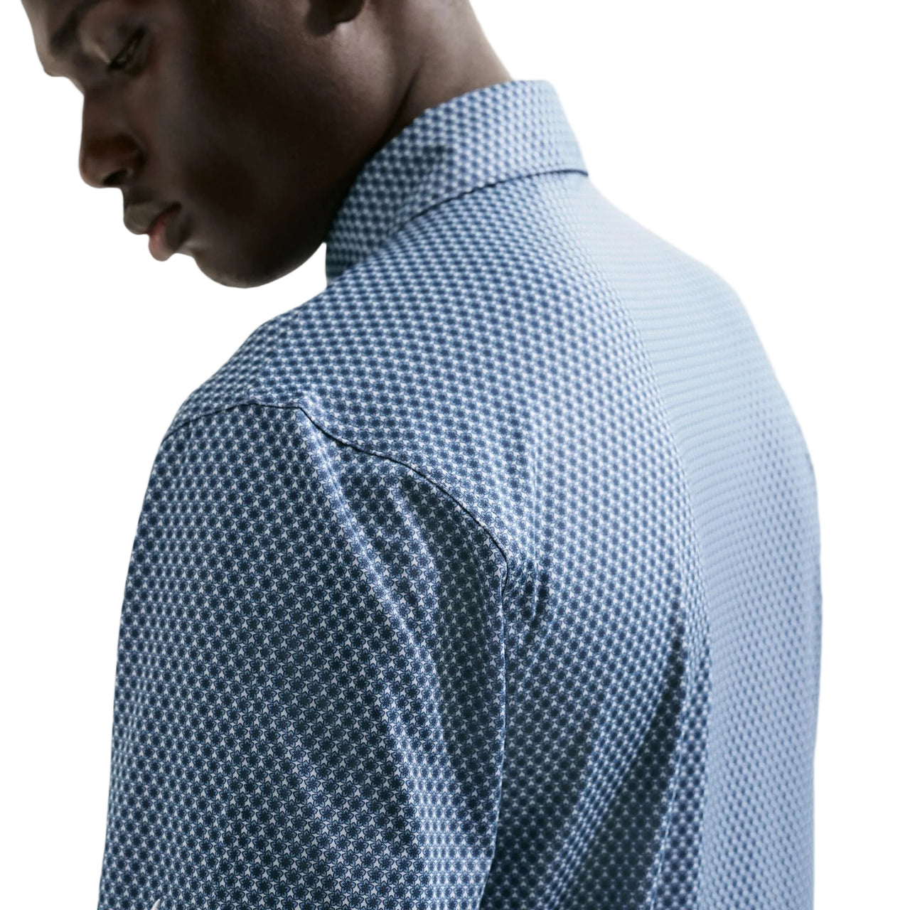 Person wearing a blue patterned shirt against a light background