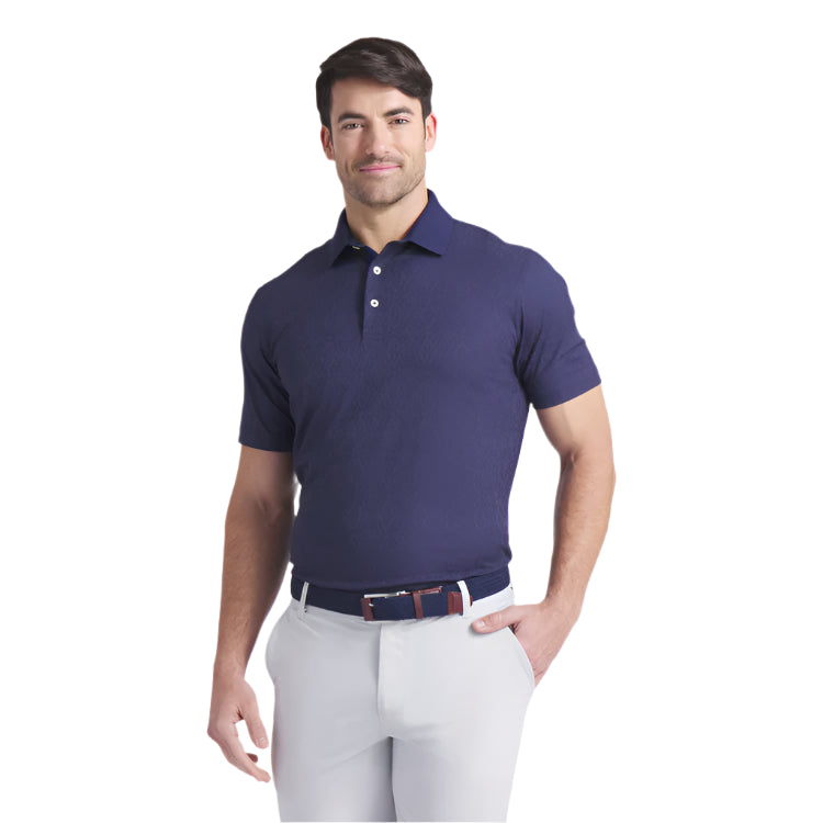 Man wearing a navy blue polo shirt and light gray pants on a white background
