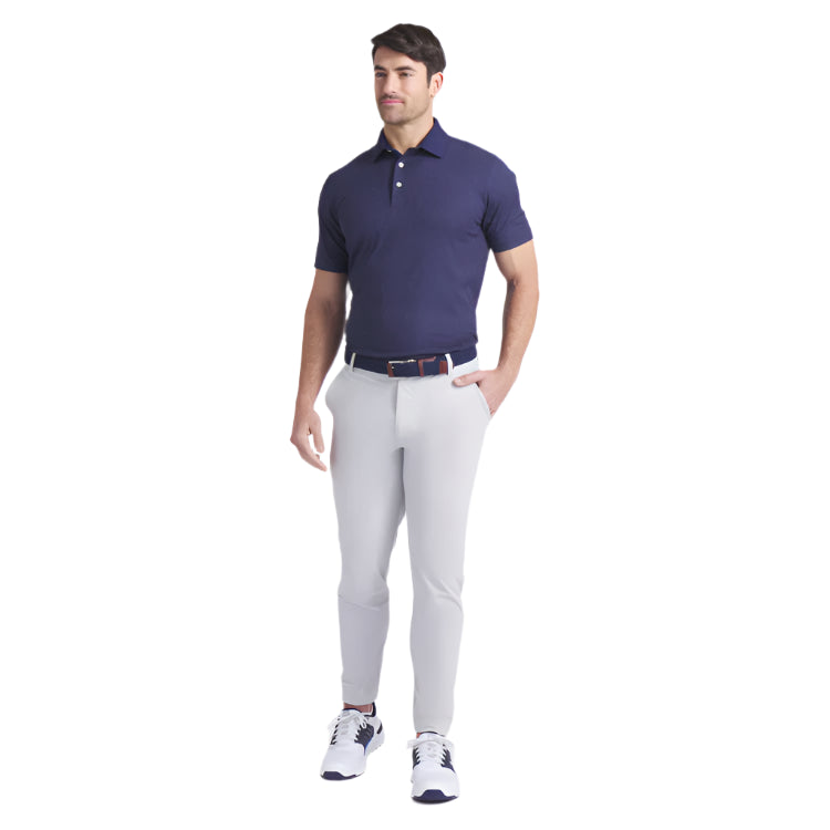 Man wearing a navy polo shirt and light gray pants on a white background