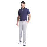 Man wearing a navy polo shirt and light gray pants on a white background