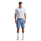 Man wearing a patterned polo shirt, blue shorts, white shoes, and a cap on a white background