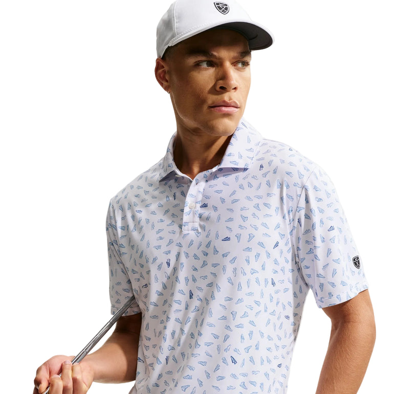 Man wearing a white patterned polo shirt and cap, holding a golf club on a light background