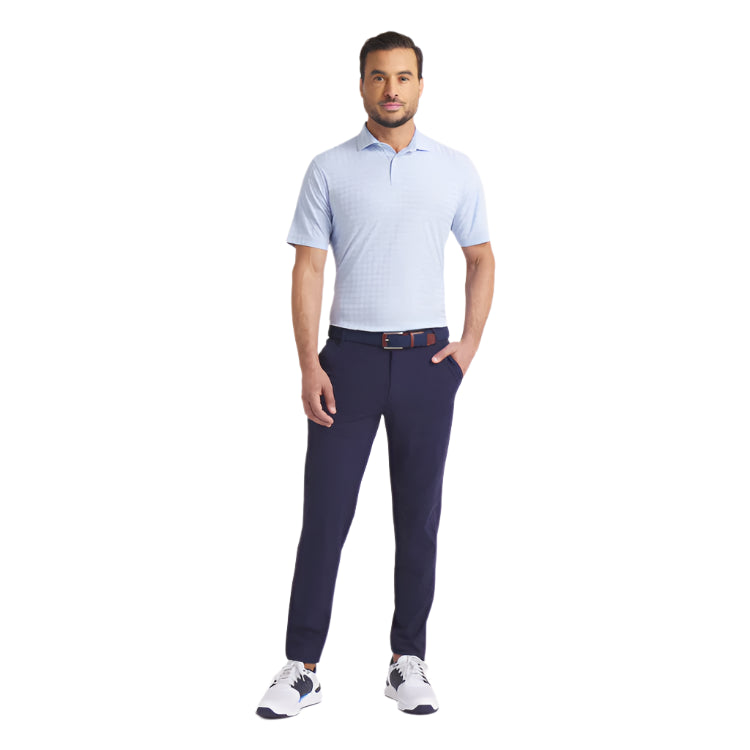 Man wearing a light blue checkered polo shirt and navy pants on a white background