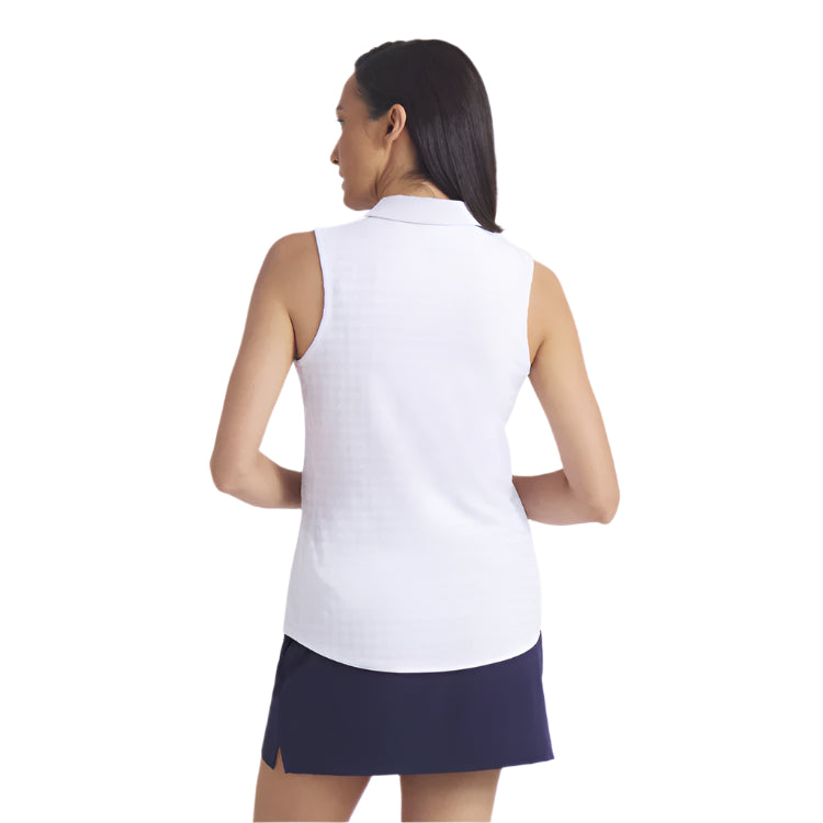 Woman wearing a white sleeveless top and navy skirt on a light gray background