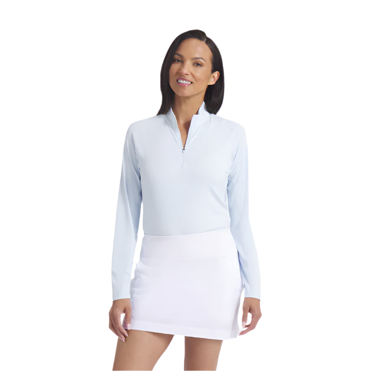Woman wearing a light blue long-sleeve top and white skirt on a white background