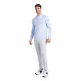Man wearing a light blue long-sleeve shirt and white pants on a white background